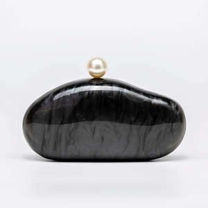 Detailed shot of smoky marble acrylic evening clutch with large pearl clasp on white backdrop