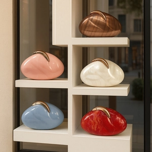 Pebble-shaped acrylic evening clutches with marble patterns and gold metal clasps