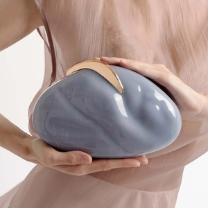 Chic pebble-shaped gray acrylic evening clutch featuring a large golden metal clasp detail