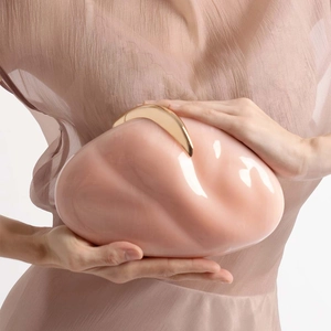 Close-up of pink acrylic clutch featuring wave texture and golden crescent buckle
