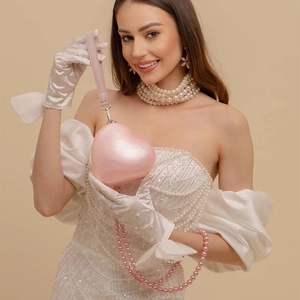 Elegant pink heart-shaped acrylic clutch bag with pearl chain shown with fashion model