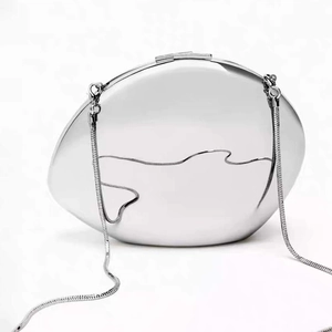 Macro detail of a polished silver pebble evening clutch with artistic wavy line pattern