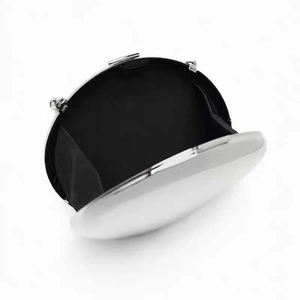 Detail view of silver round evening clutch bag with black fabric lining and metal clasp
