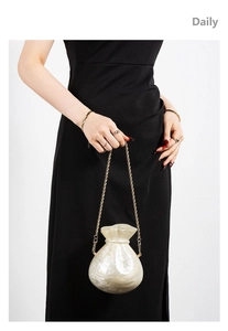 Detail of pearl white resin money bag clutch with shell texture and gold metal chain