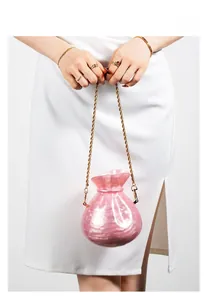 Detail view of pink pearlescent acrylic money bag clutch with gold chain strap