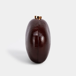 Detail of round burgundy PU leather clutch bag with elegant gold metal cylinder clasp