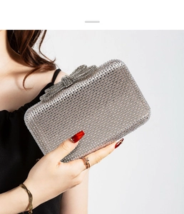 Detail of silver evening clutch bag featuring shimmering rhinestones and a bow clasp