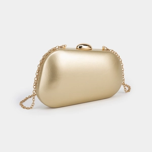 Close-up of golden hard shell evening clutch bag with pebble clasp and chain strap
