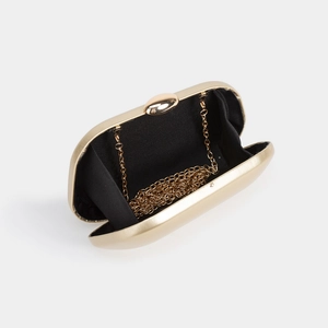 Detail of gold hard shell evening clutch bag showing black lining and metal chain strap