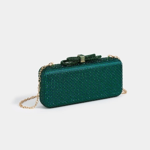 Macro view of emerald crystal clutch bag with rhinestone bow clasp and gold chain strap
