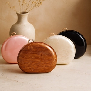 Detail view of organic oval clutch bags in wood, marble, and pearl textures with gold handles