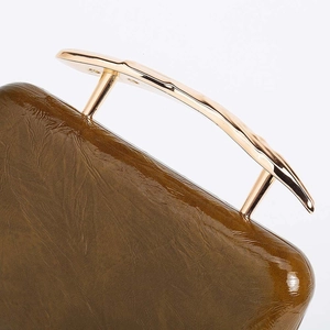 Detail of olive green PU leather bag with irregular gold-tone metallic handle