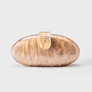 Macro shot of elegant champagne marble texture and gold textured clasp on acrylic clutch