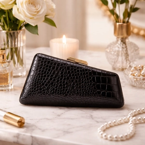 Elegant black snakeskin embossed crossbody bag with gold metal clasp on marble table