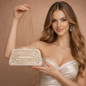 Elegant acrylic marble evening clutch bag with gold chain strap held by a model