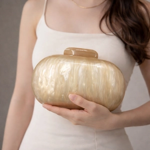 Detail of champagne gold acrylic clutch bag with marble texture held by a model
