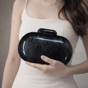 Detail of black marble textured acrylic clutch bag held by model for evening events