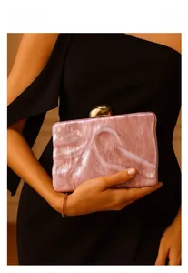 Close-up of pink marble acrylic evening clutch with geometric gold clasp detail