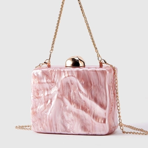 Detailed macro of pink marble texture acrylic clutch with elegant golden sphere clasp