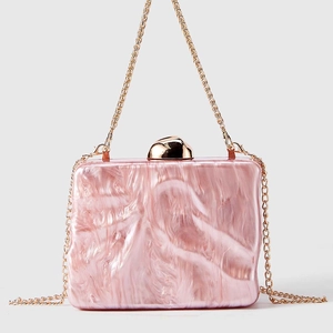 Detailed close-up of pink marble acrylic clutch bag with elegant golden chain and clasp