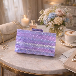 Close-up of purple pearlescent acrylic evening clutch with diamond texture on marble table