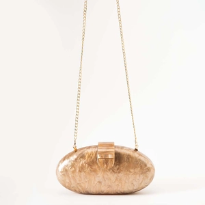 Detail of oval amber marble acrylic clutch bag with golden chain and metal clasp