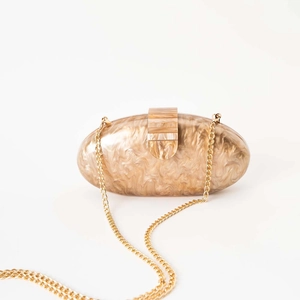 Detail of champagne marble acrylic evening clutch with a gold chain strap