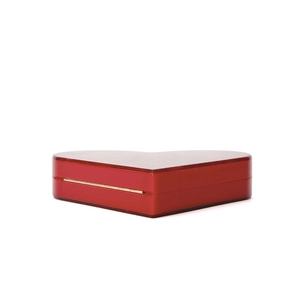 Macro detail of high-gloss red heart-shaped acrylic bag with gold metal hinge connector