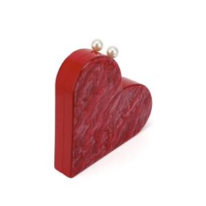 Detail view of red heart acrylic evening bag with marbled texture and pearl clasp closure