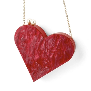 Macro detail of heart-shaped acrylic evening bag with red marble texture and pearl clasp