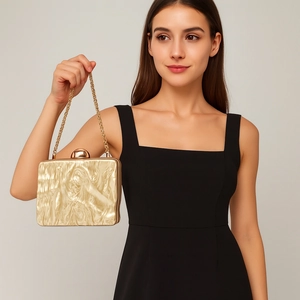 Modern gold wavy acrylic clutch bag with metal chain strap worn by a model