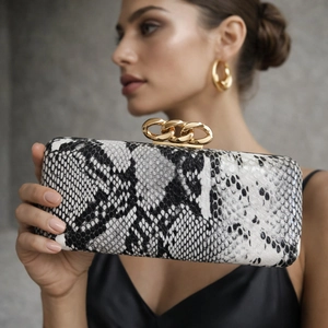 Detail of PU leather clutch featuring black and white snake print and gold chain clasp