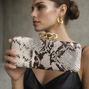 Snake print PU leather clutch bag with chunky gold chain handle held by a model