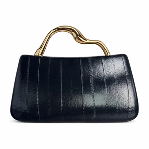 Detailed view of the dark textured patent leather and wavy gold metal handle on handbag