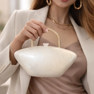 Close-up of elegant cream acrylic evening clutch with pearlescent finish and gold handle