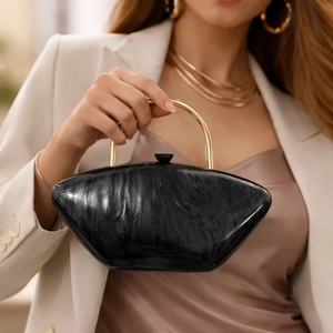 Detail of acrylic black marble evening bag with gold handle held by model in dress