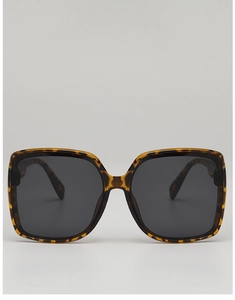 Detail of oversized square sunglasses featuring classic tortoiseshell texture and dark lenses