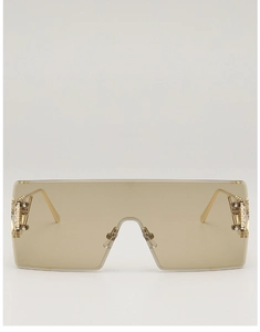 Detail of oversized rimless shield sunglasses with amber lenses and golden hardware