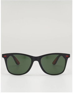 Détail de lunettes de soleil carrées noires avec verres verts et accents charnière rouges