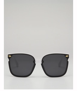 Detail of square black sunglasses with white top trim and gold metal corner accents