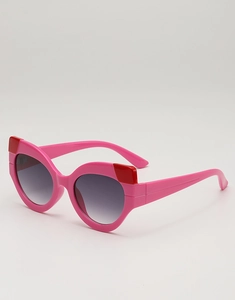 Detailed close-up of pink cat-eye sunglasses with red contrast tips and gradient lenses
