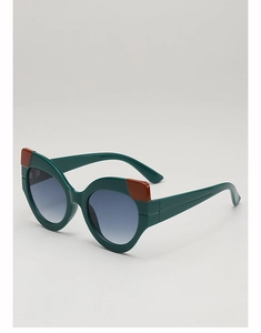 Detail view of cat-eye sunglasses featuring dark green frames with red color-block accents