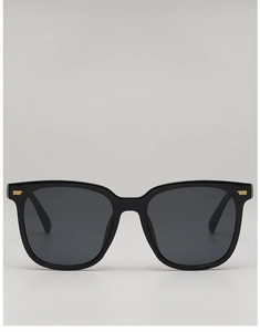 Front view of black square sunglasses with gold metal accents on the frame corners