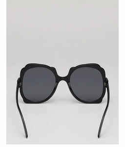 Close-up of oversized black square sunglasses with glossy frames and dark grey lenses