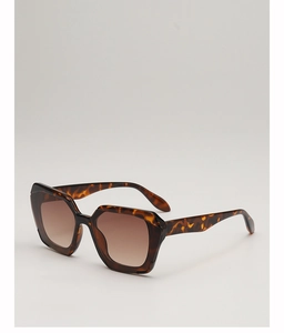 Detail of polygonal brown tortoiseshell sunglasses with brown gradient lenses on gray background