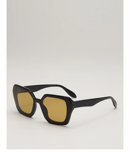 Detail view of retro polygonal sunglasses with thick black frame and amber lenses