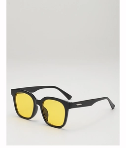 Detail einer schwarzen eckigen Sonnenbrille mit gelben Gläsern und silbernen Akzenten