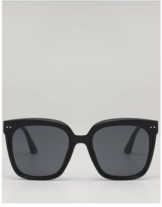 Detail view of square black sunglasses with silver rivet accents and grey lenses