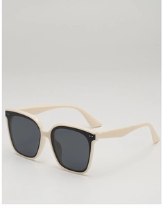 Detail view of cream-colored rectangular sunglasses with silver rivets and black inner frame