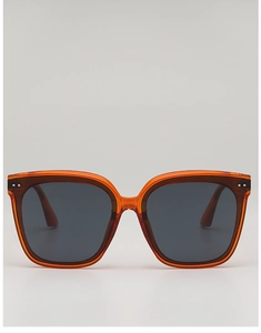 Close-up of square translucent orange sunglasses with rivet detail and grey lenses